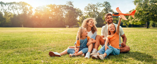 Family smiling while sitting on the grass